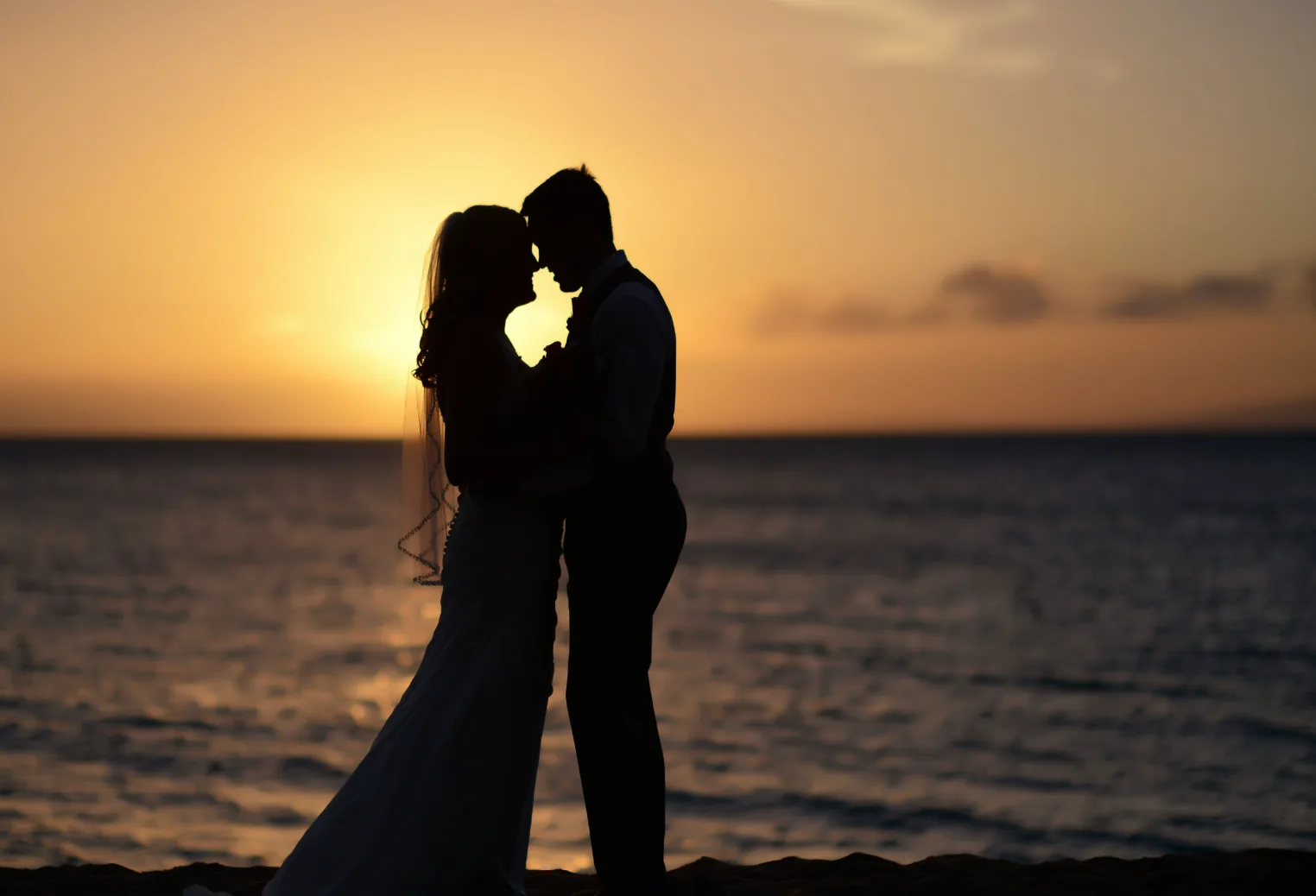Ein Paar als Silhouette vor dem Sonnenuntergang über dem Meer